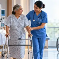 Nurse assisting a patient with early ambulation using a walker in a hospital